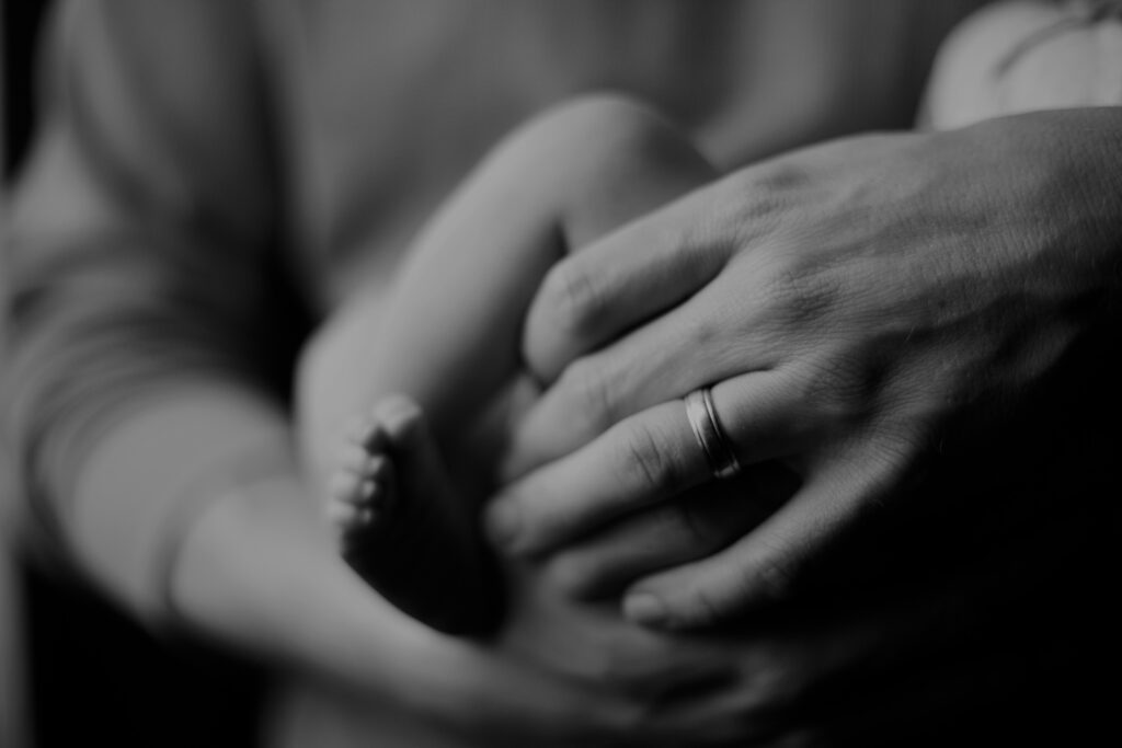 Parent gently holding newborn baby’s foot, symbolizing parenting care, family love, and early childhood support.